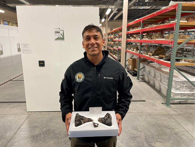 Community Volunteer Ambassador smiles while holding artifact in a box