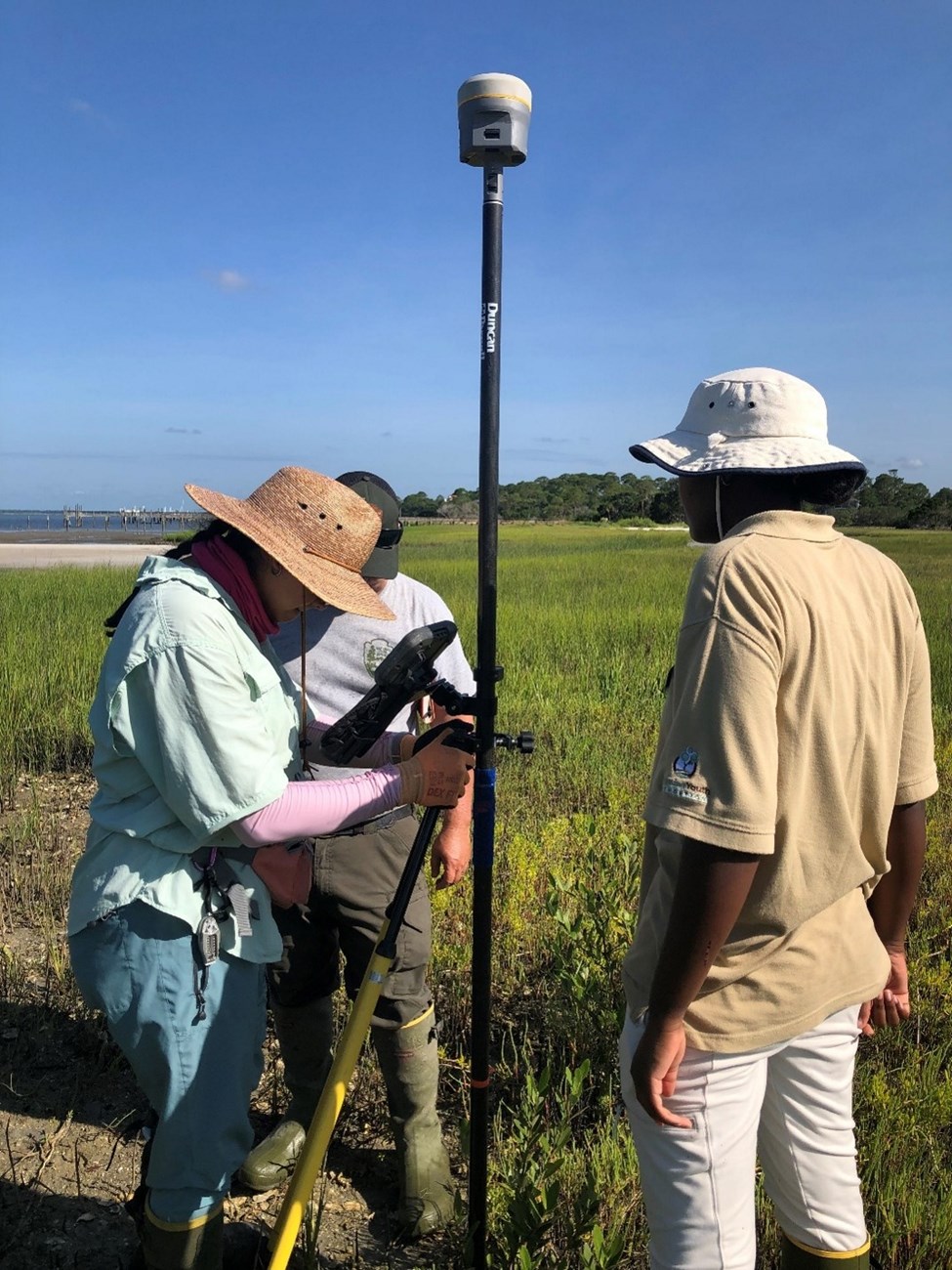 Mangrove Marker 3 people marking point in marsh