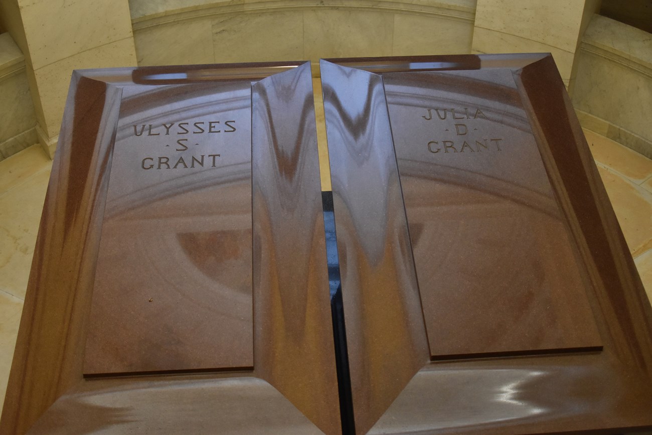 Two red granite sarcophagi next to each other with writing on the top