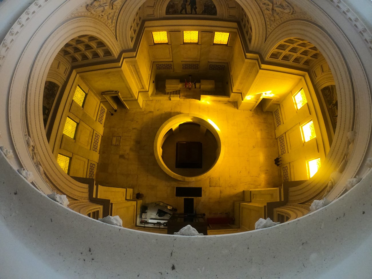 Birds eye view of white granite floor and surrounding walls and two dark sarcophagi on the bottom of room