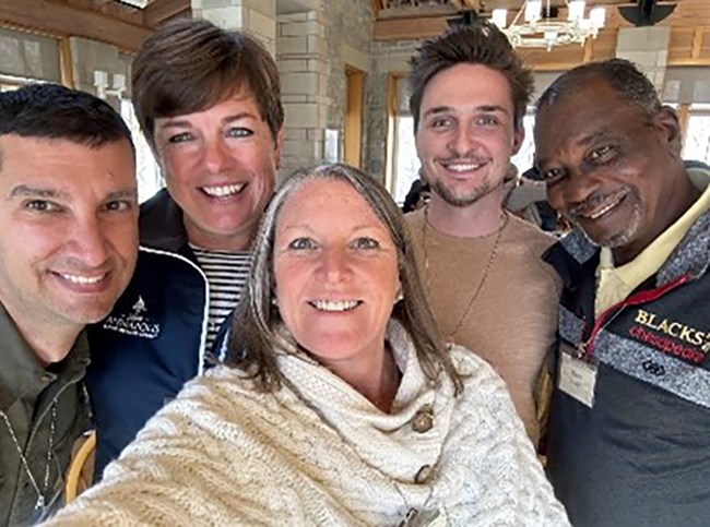 A group of five people smile for a selfie inside a room.