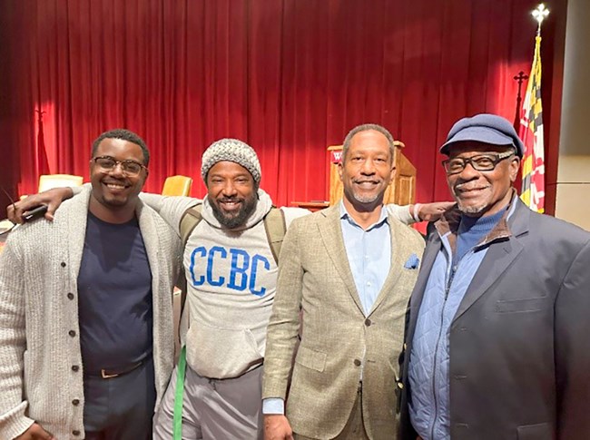 Four African American men pose inside an auditorium.