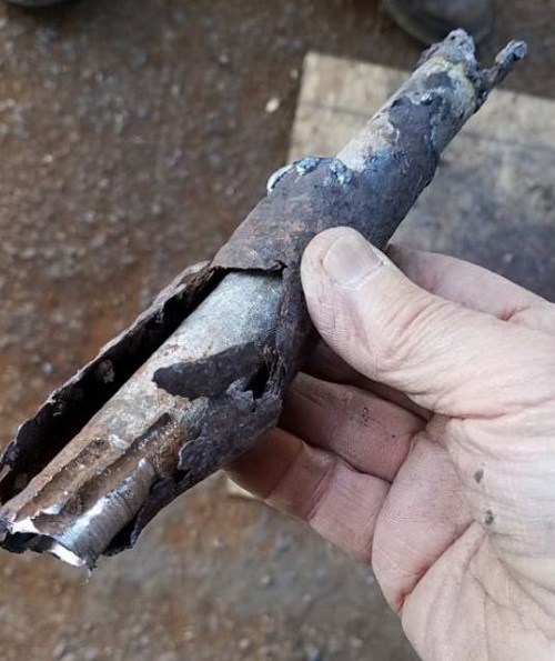 A section of deteriorated pipe with a more solid pipe inside it.
