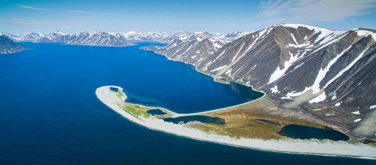 Aerial view of a white sand spit and fjords.