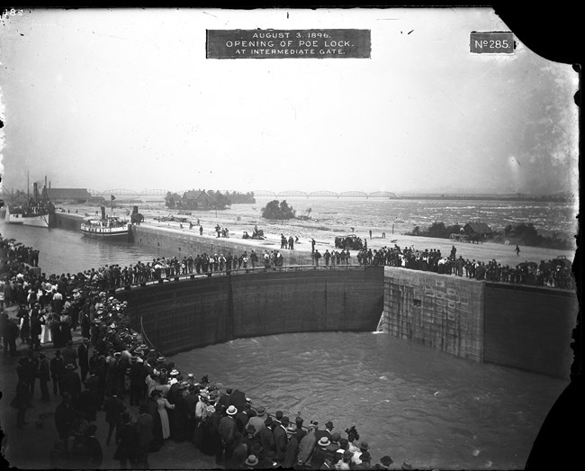 Historic photograph of the opening of the Poe Lock in Sault Sainte Marie, Michigan. The words at the top of the photograph read 'August 3, 1896. Opening of Poe Lock. At Intermediate Gate."