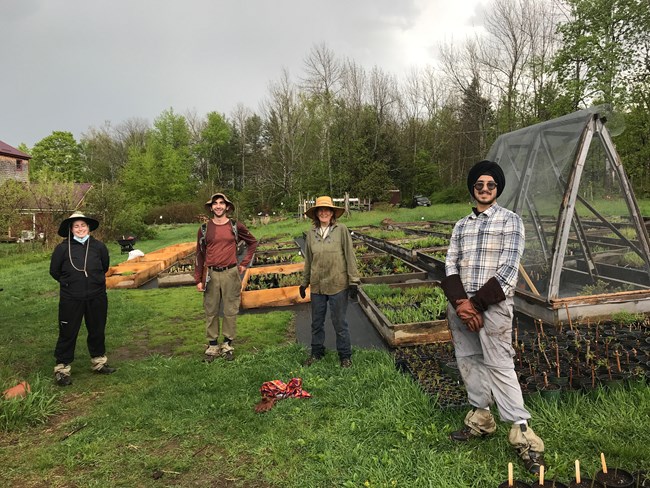 Four people pose for a photo in front of raised garden beds