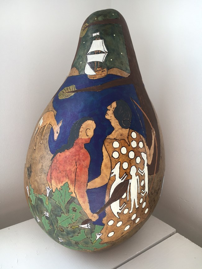 A gourd painted with two men in traditional American Indian clothing