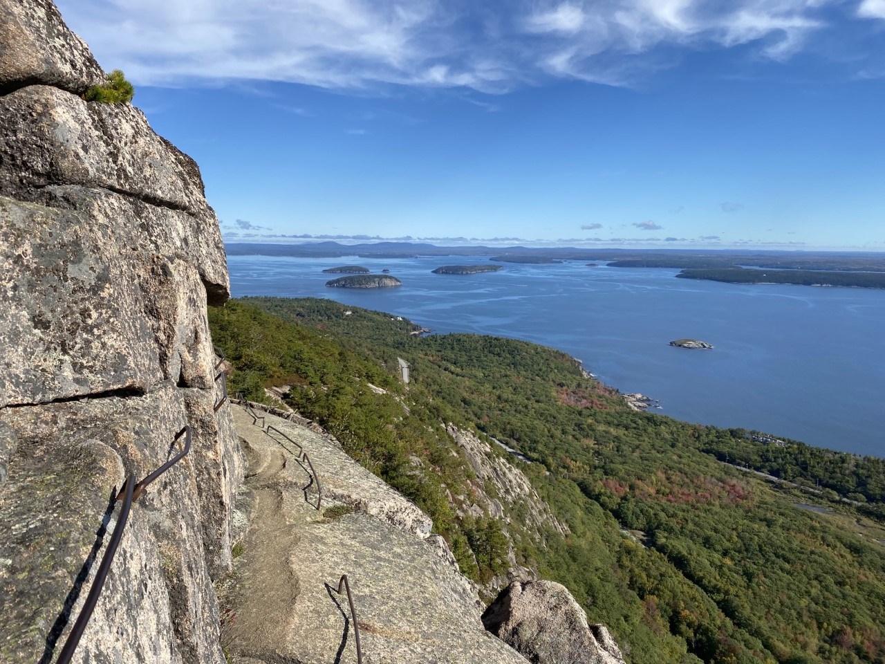 granite cliffs with iron rungs high up above an ocean and forested view