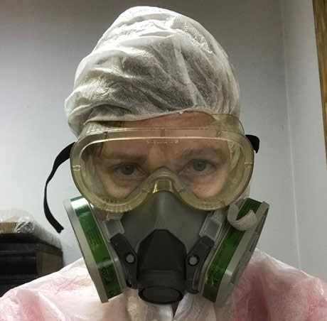 A woman with a respirator, protective goggles, and protective suit covering her clothes and hair A woman with a respirator, protective goggles, and protective suit covering her clothes and hair