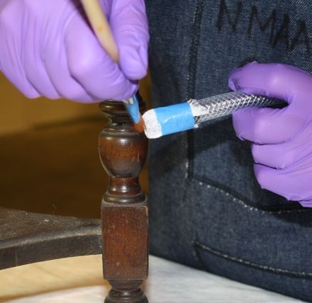 Worker using a brush to dislodge mold from from wooden furniture while vacuuming the loose mold spore Worker using a brush to dislodge mold from from wooden furniture while vacuuming the loose mold spore