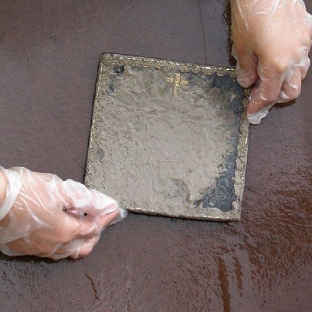 Small heirloom textile completely coated in dirt and mud from a flood.