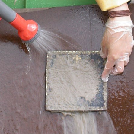Someone rinsing the dirt and mud from the textile Someone rinsing the dirt and mud from the textile
