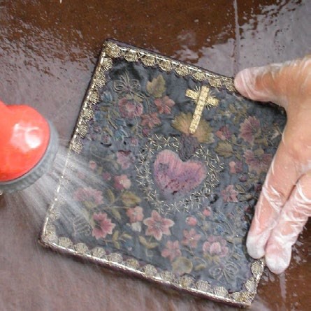 The final photograph shows the intricate detail and various colors of the cleaned textile once the mud and dirt are removed. The final photograph shows the intricate detail and various colors of the cleaned textile once the mud and dirt are removed.