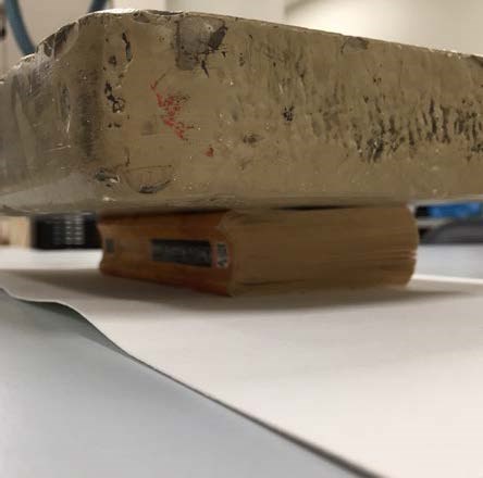 Next, a weighted brick is shown on top of the book in effort to flatten the pages.