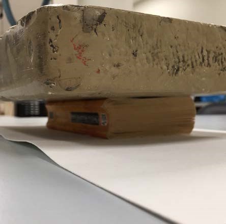Next, a weighted brick is shown on top of the book in effort to flatten the pages. Next, a weighted brick is shown on top of the book in effort to flatten the pages.