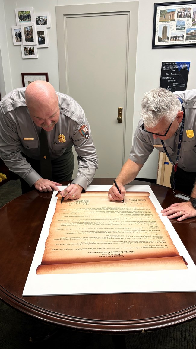 Two people in uniform sign large proclamation