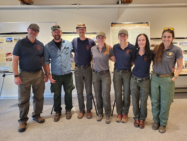 A group of fire ecologists stand together indoors and smile.