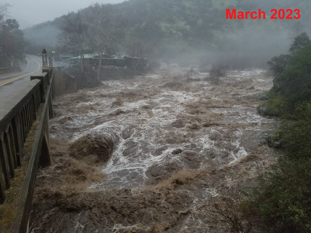 View from bridge of high river flow, with most large rocks covered