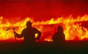 Firefighters silhouetted against tall flames