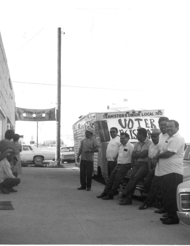 A group of men stand in front of a truck with a Voter Registration drive