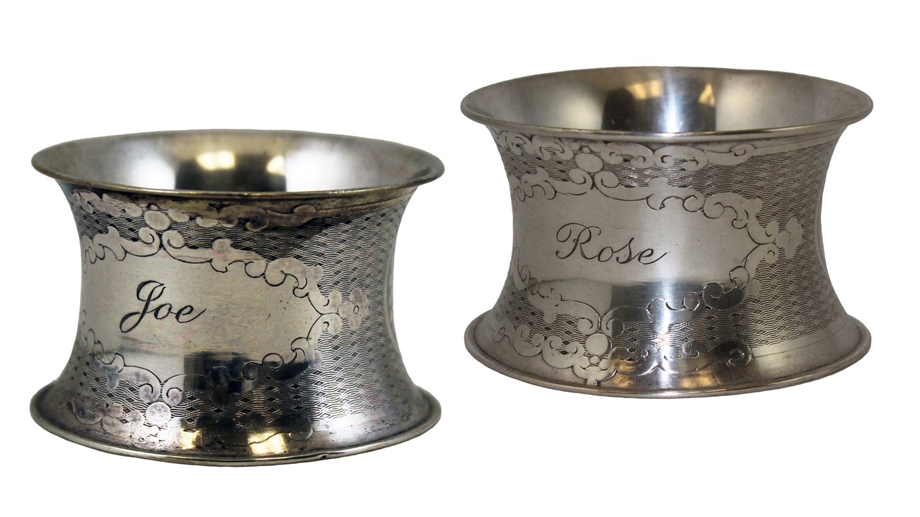 Two silver napkin rings with floral decorations and names Rose and Joe engraved in medallions.