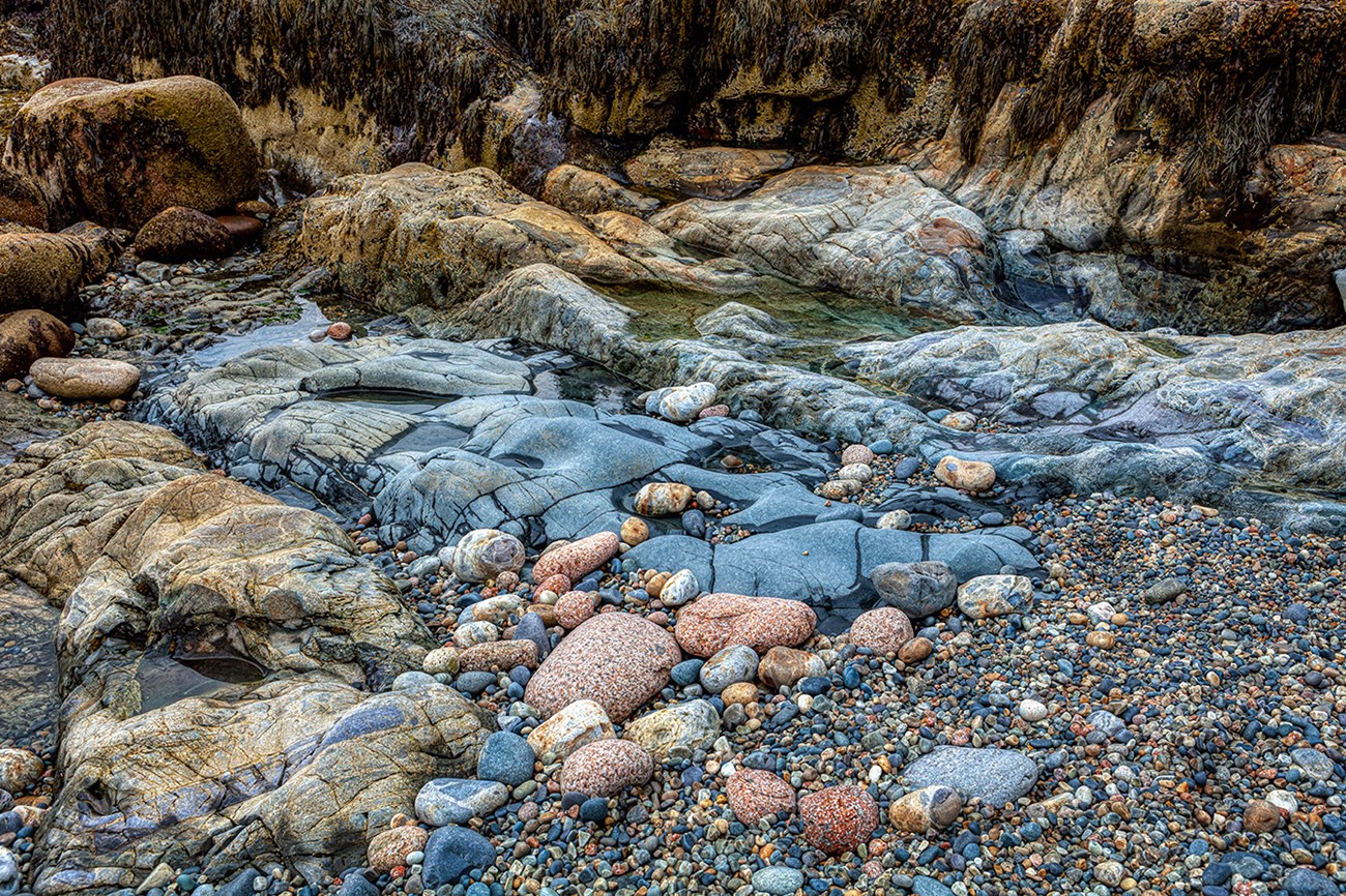 Diverse stapes, sizes and colors of stones, from pebbles, gravel, boulders to granite ledges