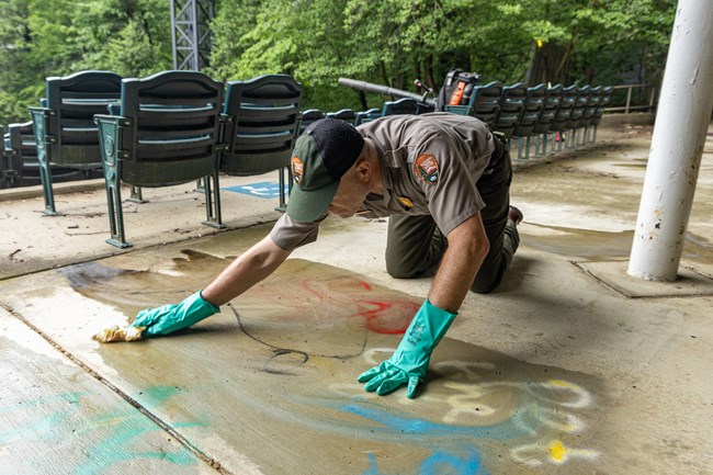 ROCR_Graffiti Removal_20250617_KGraczyk_031 A man in NPS uniform scrubs a concrete floor by hand.