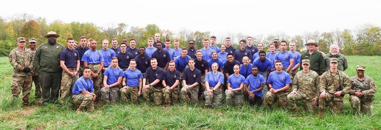 ROTC Cropped Color photograph of a large group of ROTC cadets in three rows all looking at the camera. They are wearing various shades of blue t-shirts