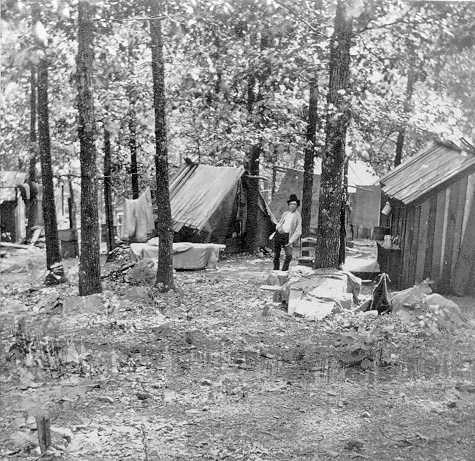 A man surrounded by shanties in the woods