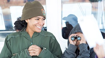 Park Ranger smiles at child using binoculars