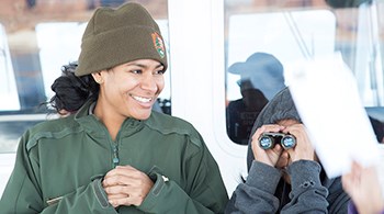 Ranger Edmonia with kid Park Ranger smiles at child using binoculars