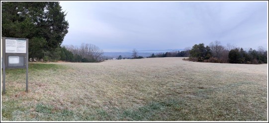 Photo of a viewpoint that includes low-growing grass in shades of brown and green, irregularly bordered by trees with and without leaves. The ground level drops in the distance, and the sky is a hazy blue. Photo of a viewpoint that includes low-growing grass in shades of brown and green, irregularly bordered by trees with and without leaves. The ground level drops in the distance, and the sky is a hazy blue.