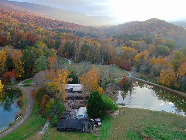 Aerial image of ponds and hills in autumn with farm structures in center