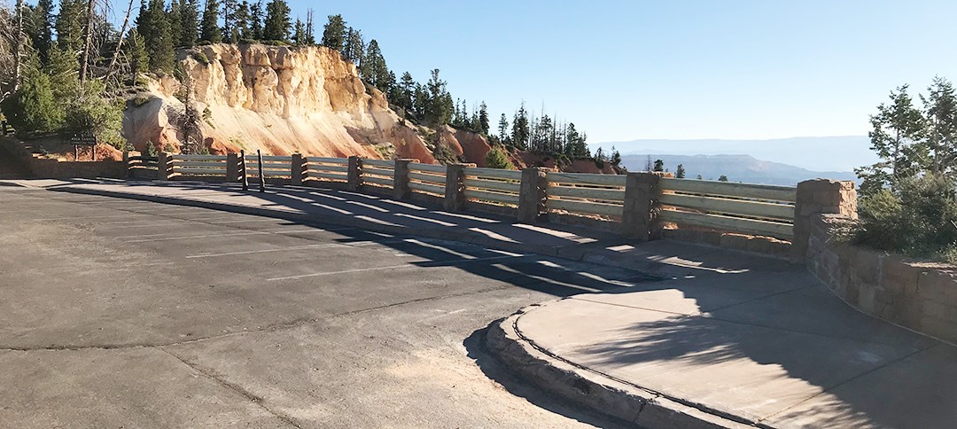 Repaired Viewpoint Overall A broad paved viewpoint with fresh timber railings and stone columns inbetween. Bright limestone cliffs stand beyond.