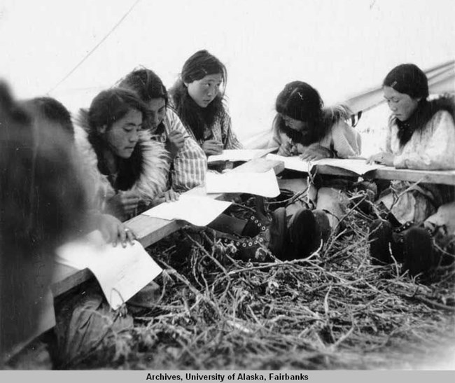 Black-and-white photograph of young Nunamiut women in school inside a wall tent Black-and-white photograph of young Nunamiut women in school inside a wall tent
