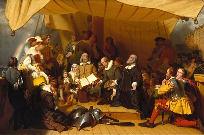 group of people on a ship praying with a rainbow in the background.