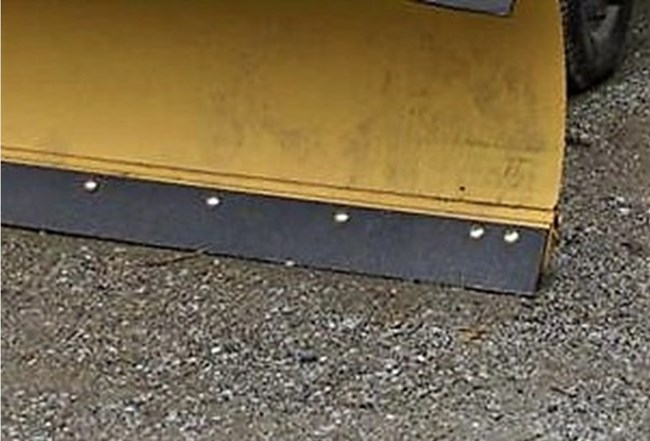A close up of the rubber edge of a yellow snow blow