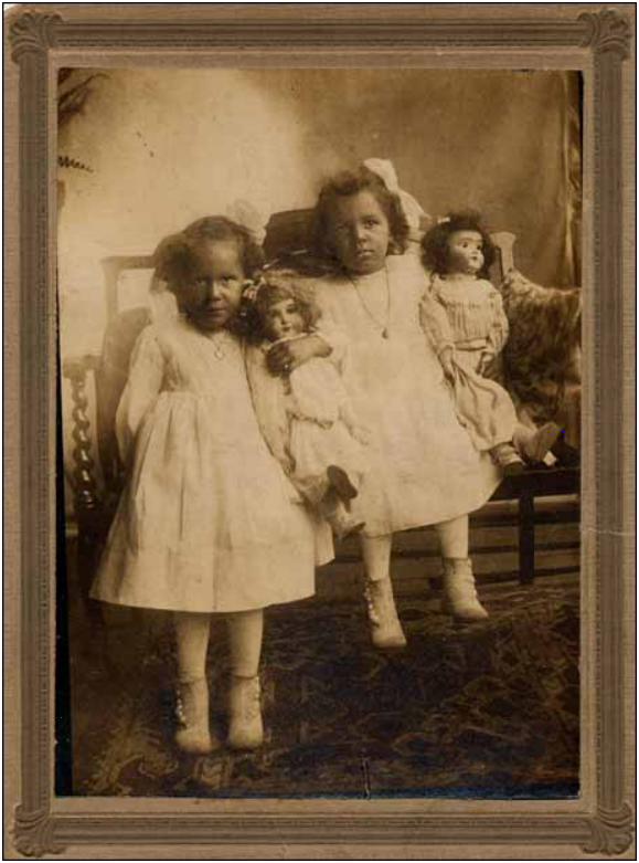 Two young girls holding dolls