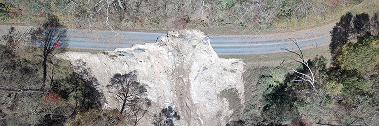 Road damage along Blue Ridge Parkway. Aerial view of forest and road where a landslide has obliterated a section of road.