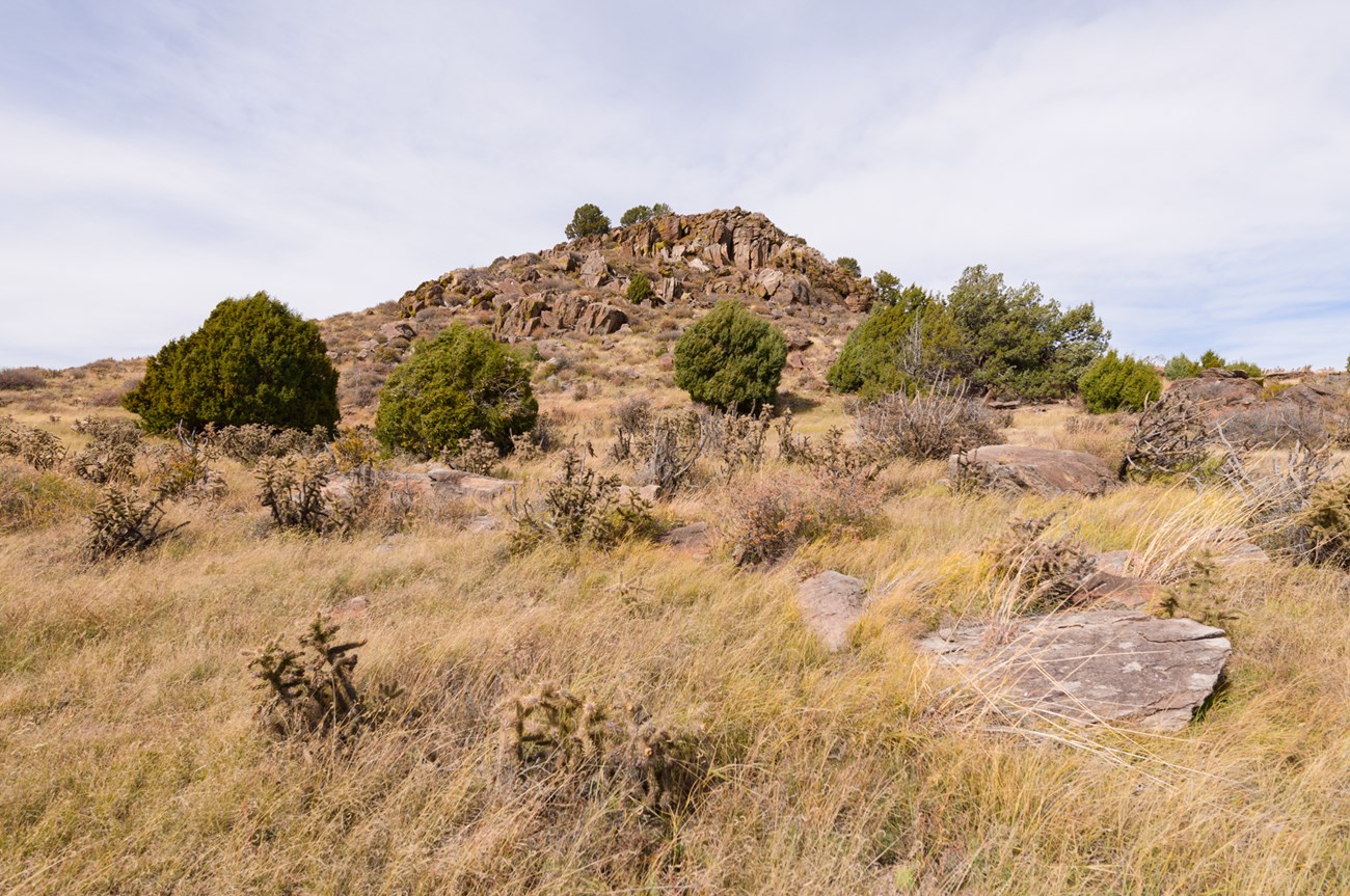 Rocky formation rising from a dry tallgrass prairie