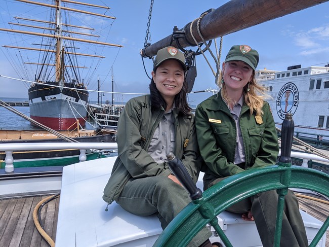Photo of Anne Monk and Sabrina Oliveros in their uniforms smiling on top of a ship.