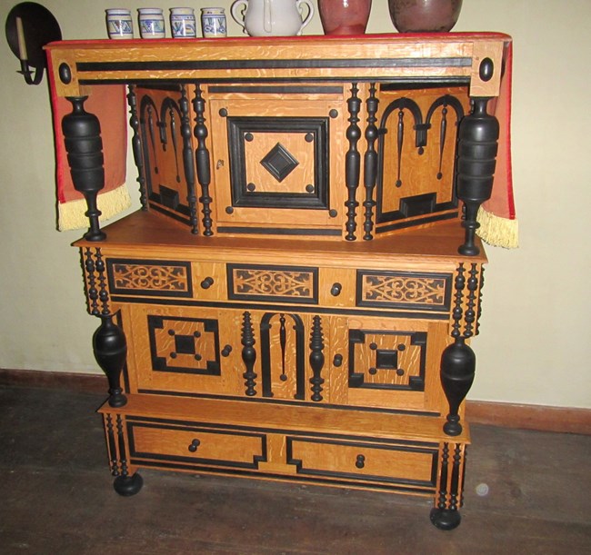 cupboard with lightly stained wood and dark wood intricate decorations