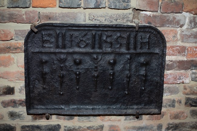 Black cast iron fireback with raised decorations and initials EH dated 1655.
