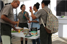 SAJU employees thank Indra Brugueras while having some breakfast before work. A group of people gather around a small plastic table to get coffee and snacks.