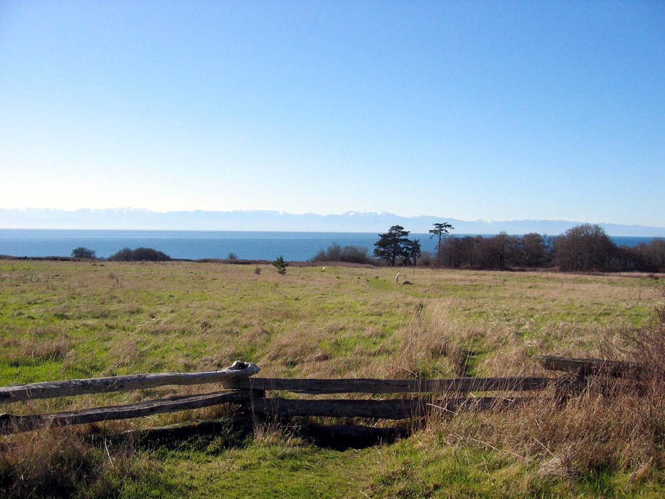 San Juan Island National Historical Park fence in front of prairie with mountains in the distant background