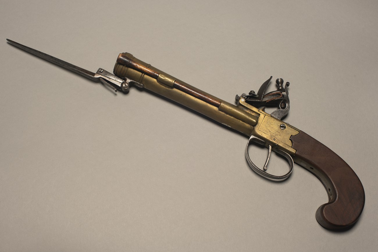 11.5 inch brass, iron and walnut pistol with spring bayonet extended.