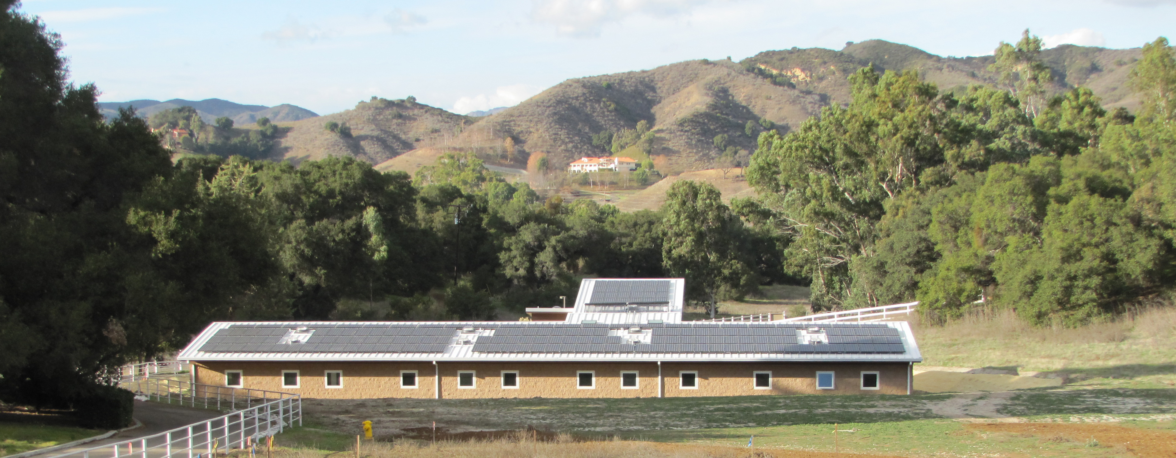 The intern center building, with solar panels on the roof, nestled in the hills of Santa Monica with trees surrounding