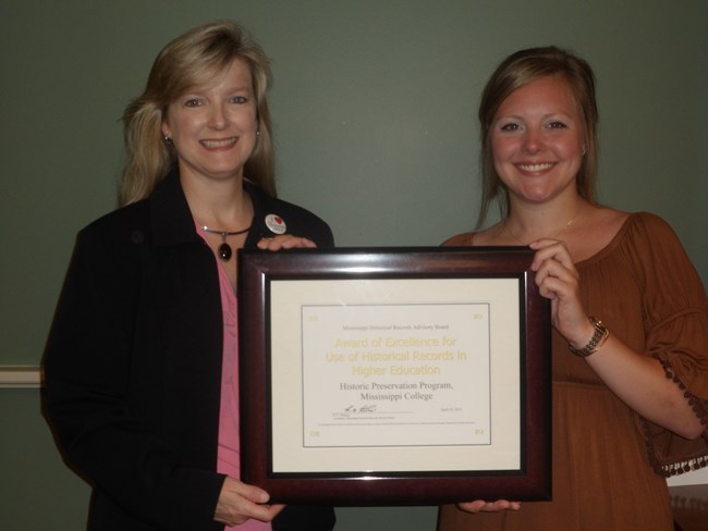 Tricia Nelson and an unidentified graduate hold a framed degree certificate. Tricia Nelson and an unidentified graduate hold a framed degree certificate.