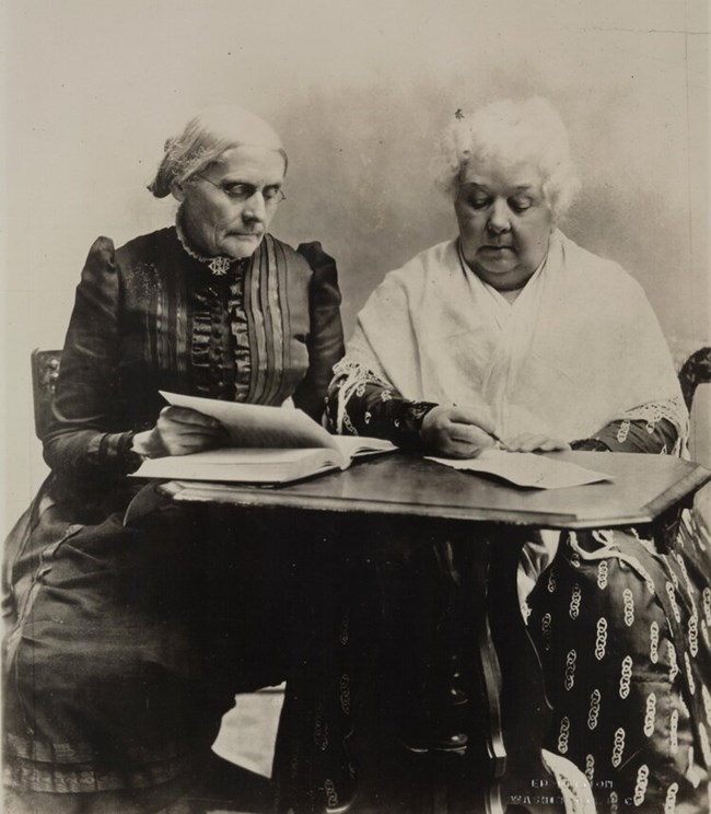 SBA+and+ECS+LOC Two women, one seated, one standing, look at books. LOC
