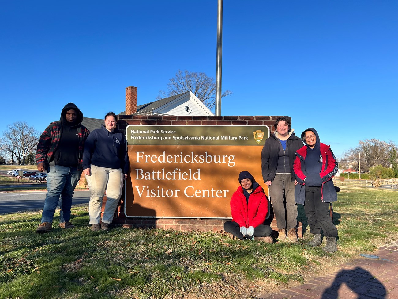 SCA Crew full Five Student Conservation Association volunteers stand around the brick road sign for the Fredericksburg Battlefield Visitor Center.